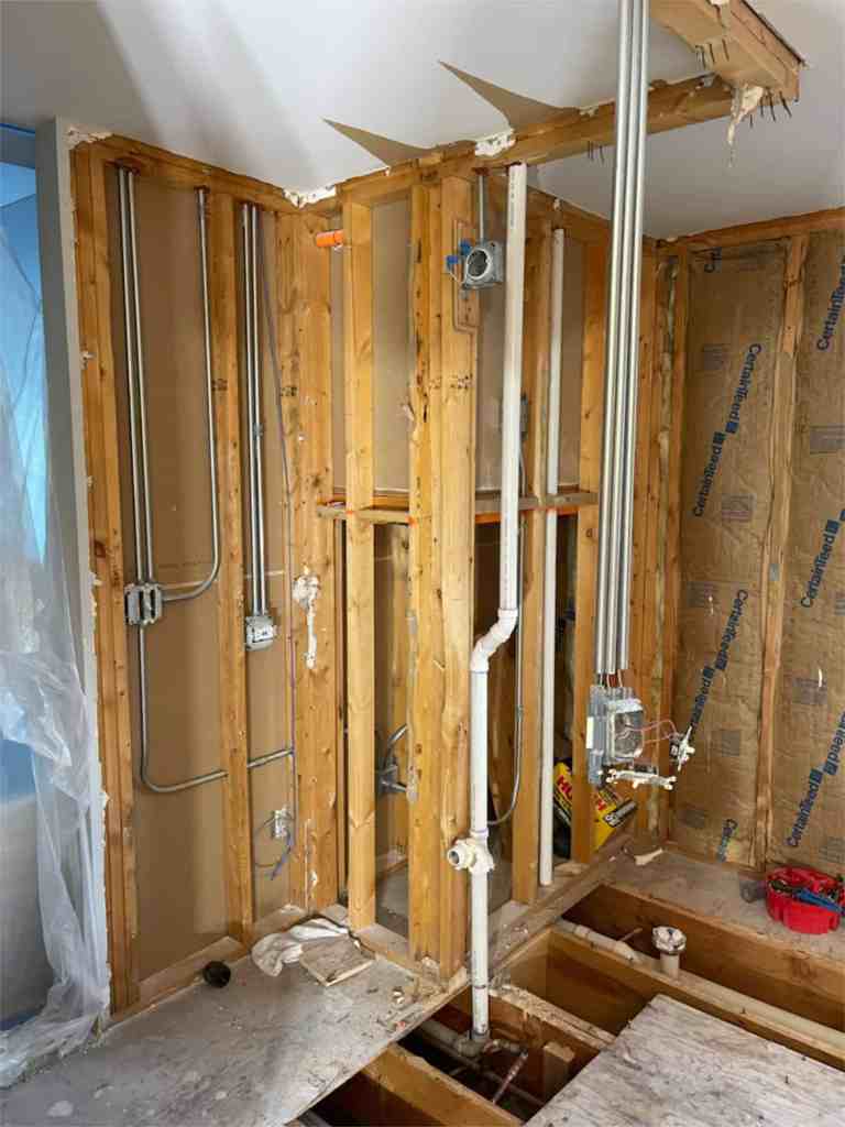 Photo of bathroom walls opened and plumbing exposed during bathroom renovation